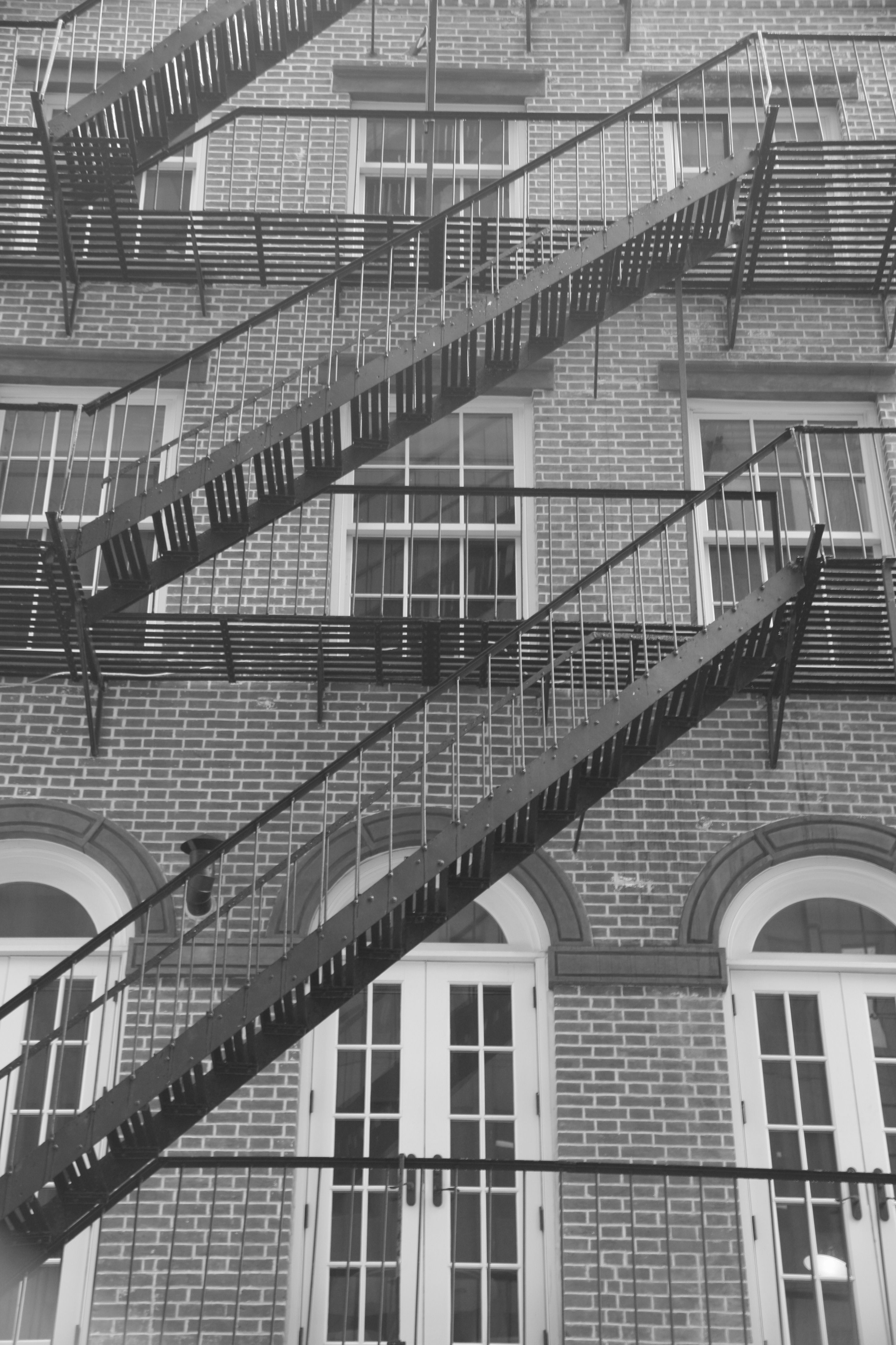A black and white photo of a tenement building with crisscrossing fire escapes in New York City
