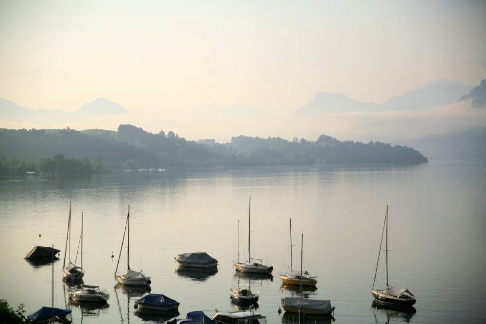 A peaceful, shining lake with boats floating on the surface in the foreground