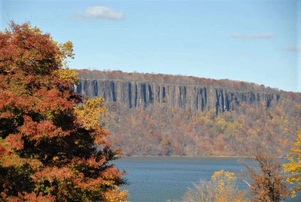 a cliff at the edge of a blue lake, with golden foliage in the foreground