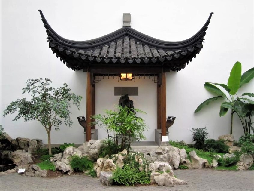 an indoor zen garden with a small pagoda surrounded by green plants and stones