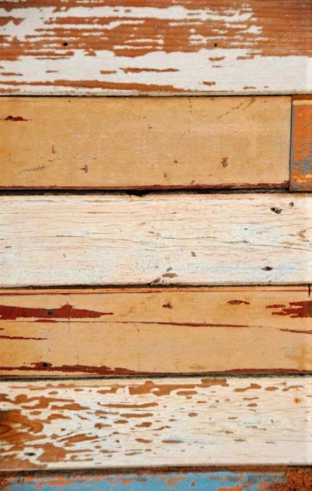 A close-up photo of weathered wooden planks with a layered texture and varying shades of brown and tan.