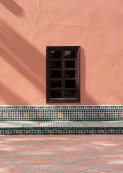 A small square window in a peach terra-cotta wall