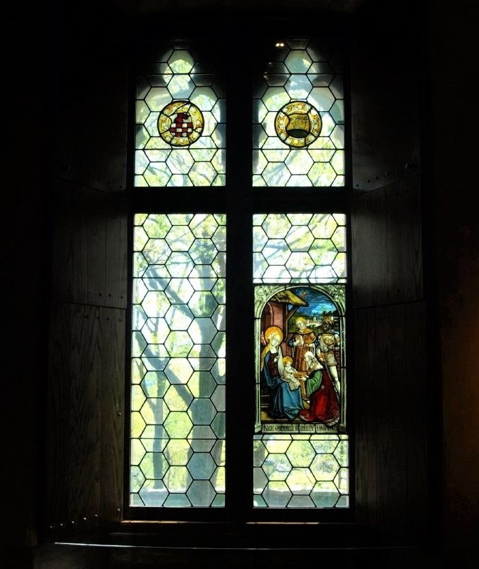 An illuminated stained-glass window whose panels are primarily lime-green and feature a Biblical scene