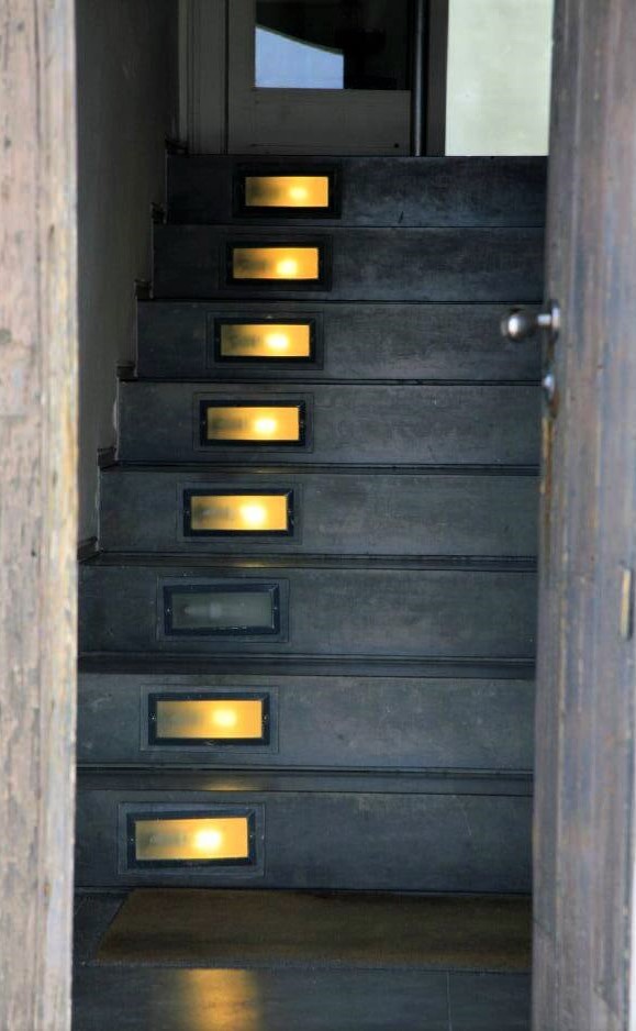 A modern gray staircase with rectangular lights inset into the steps, and one of the lights is broken
