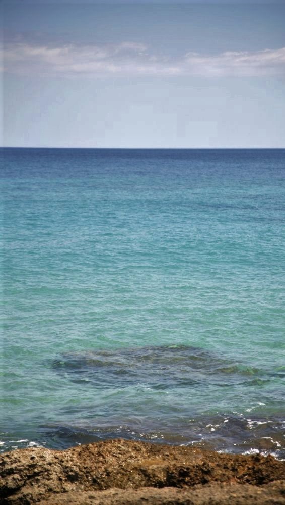 A photo of the ocean with coastal rocks visible in the foreground