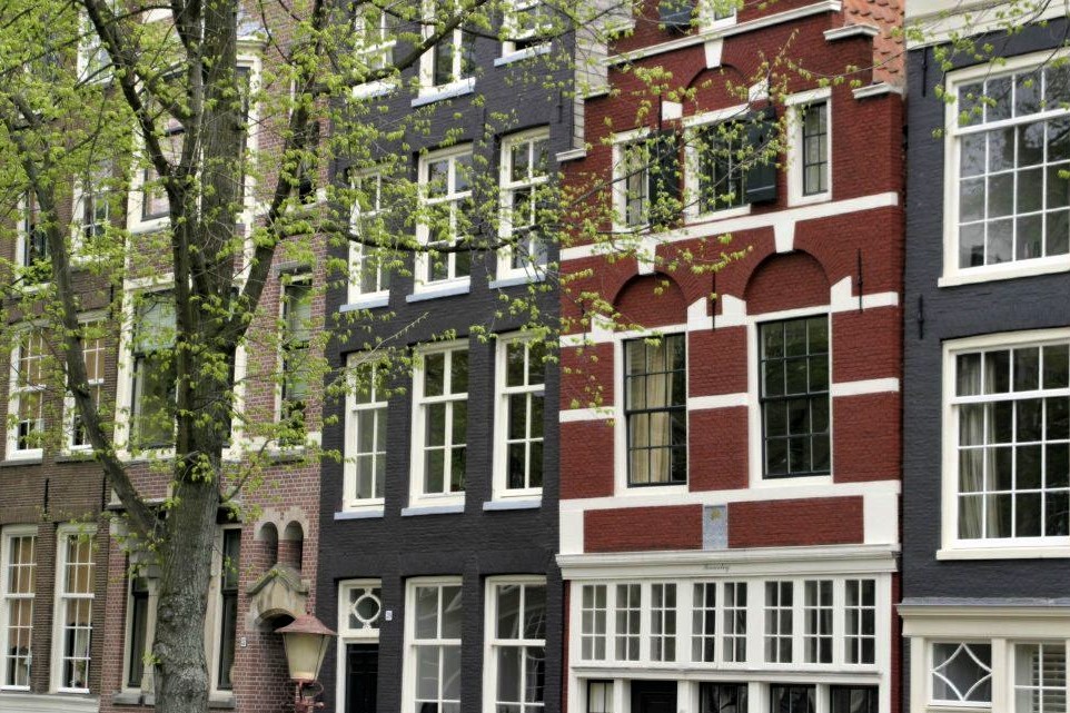 A row of ornate, narrow brick buildings along a canal