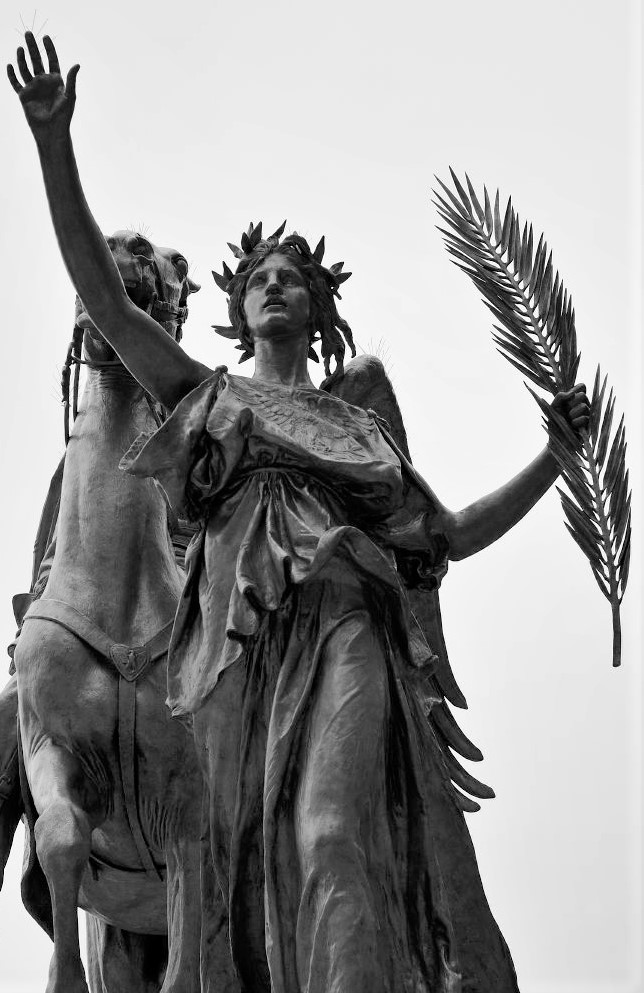 A statue of a woman holding an olive branch with her other arm raised