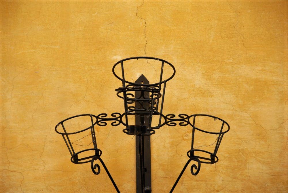 A yellow stone wall featuring wrought iron sconces