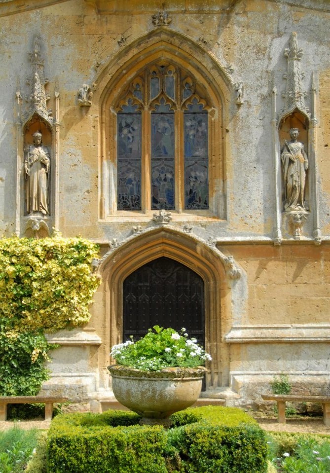 An ornate stone doorway in the side of the castle, flanked by two sculptures of saints