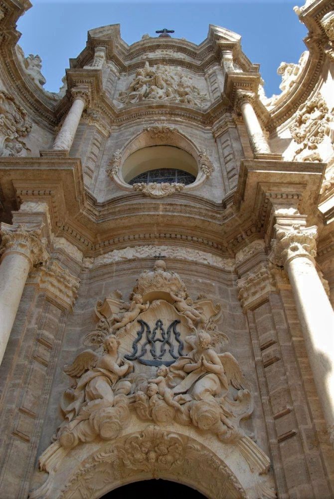 A view from the ground looking up the facade of an ornate stone cathedral