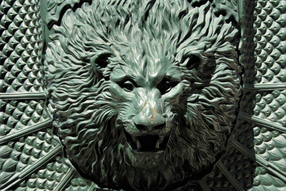 A green copper sculpture of the head of a lion