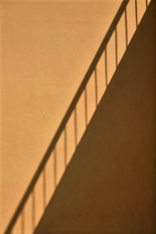 A silhouette of a staircase cast on a beige stone wall