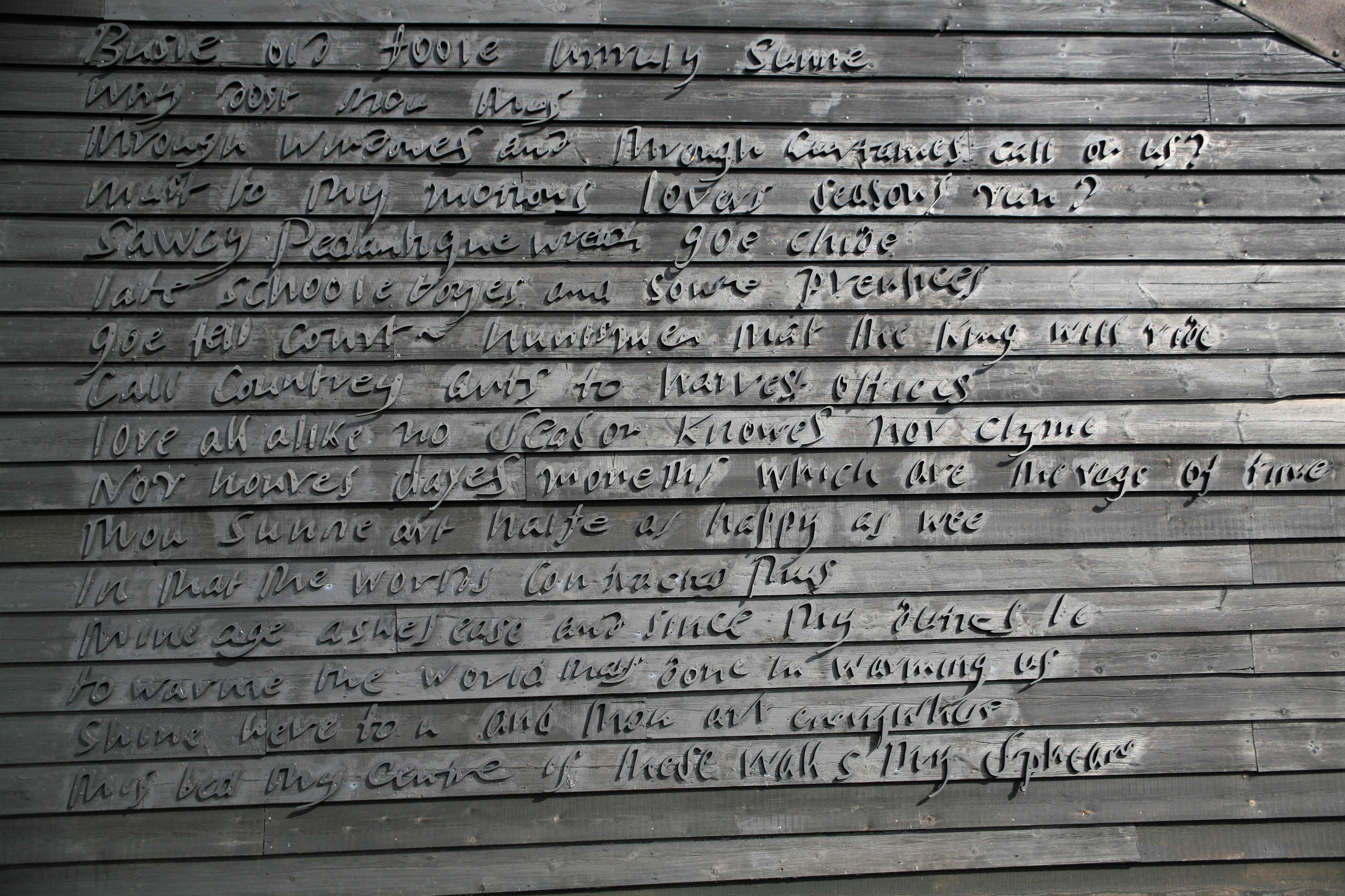 A caligraphic inscription carved into the wooden side panels of the outer wall of a cottage