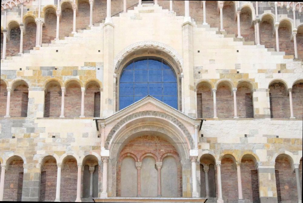 A pale sandstone facade of a church featuring numerous archways