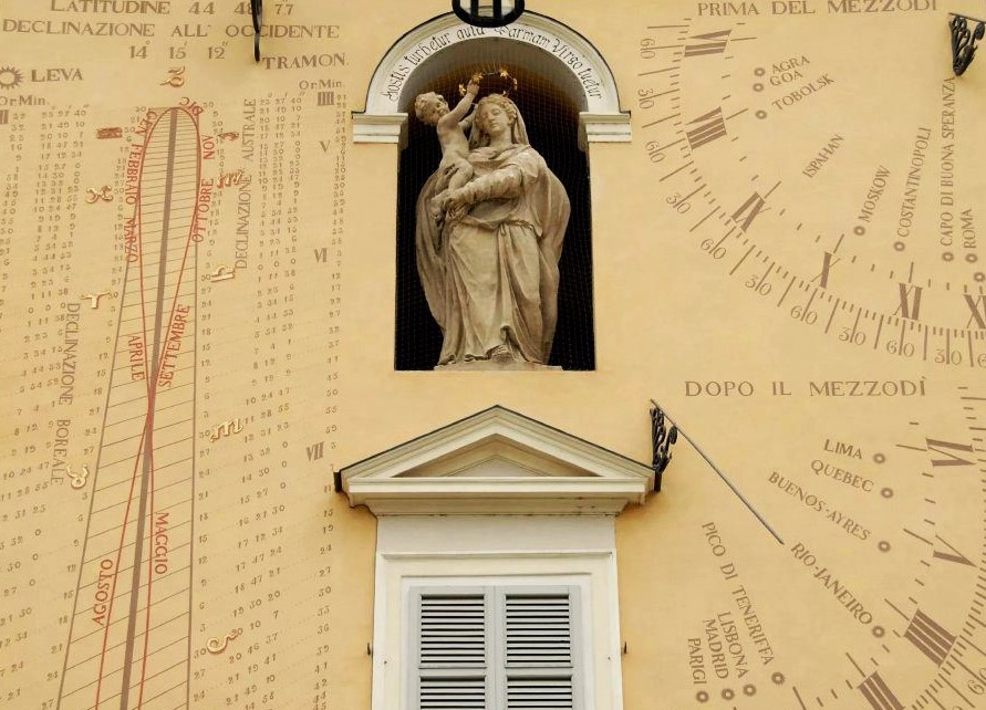 A pale yellow wall decorated in celestial calculations, at the centre of which is an alcove where a statue of Jesus and Mary is nestled