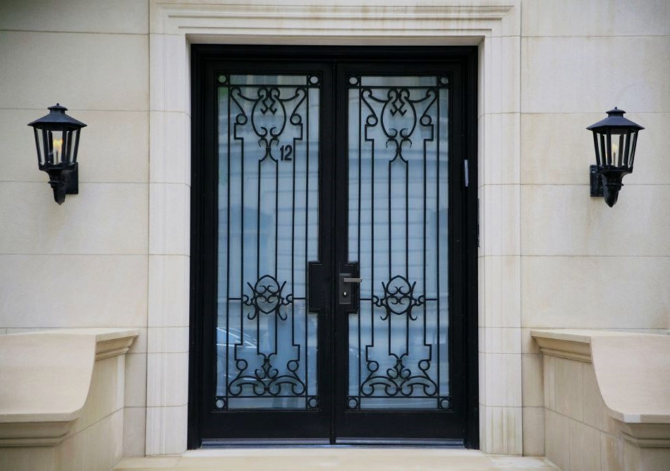 An entryway to an elegant sandstone building, featuring an ornate glass door with a wrought iron lattice, flanked by iron lanterns