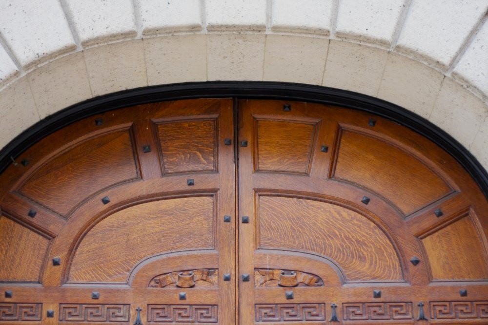 The arched upper half of an ornately carved wooden door