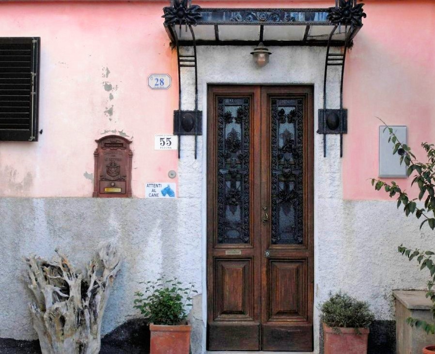 The entryway of an old peach coloured villa