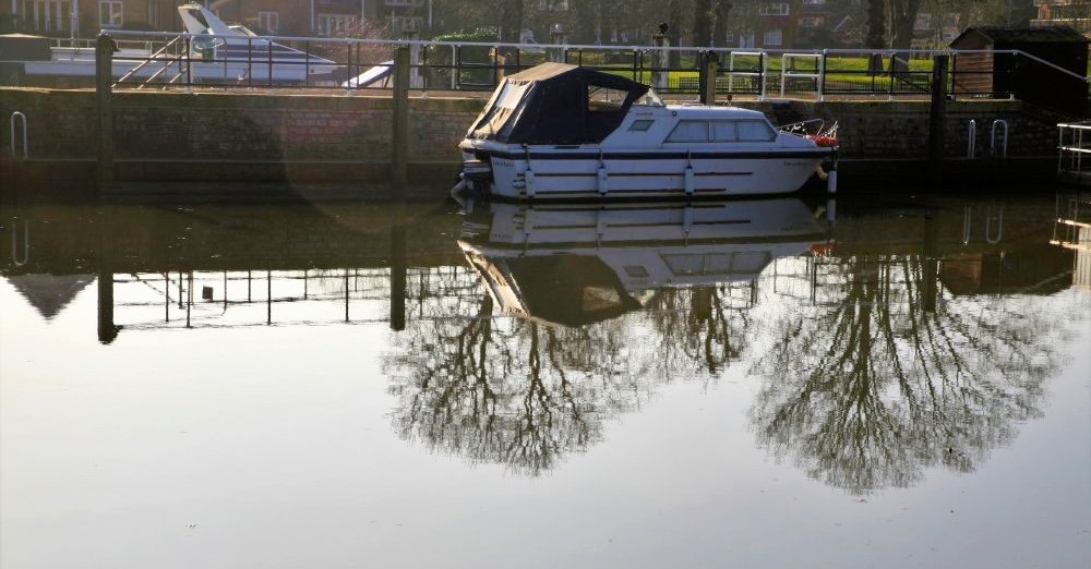 A boat in dock mirrored in the water