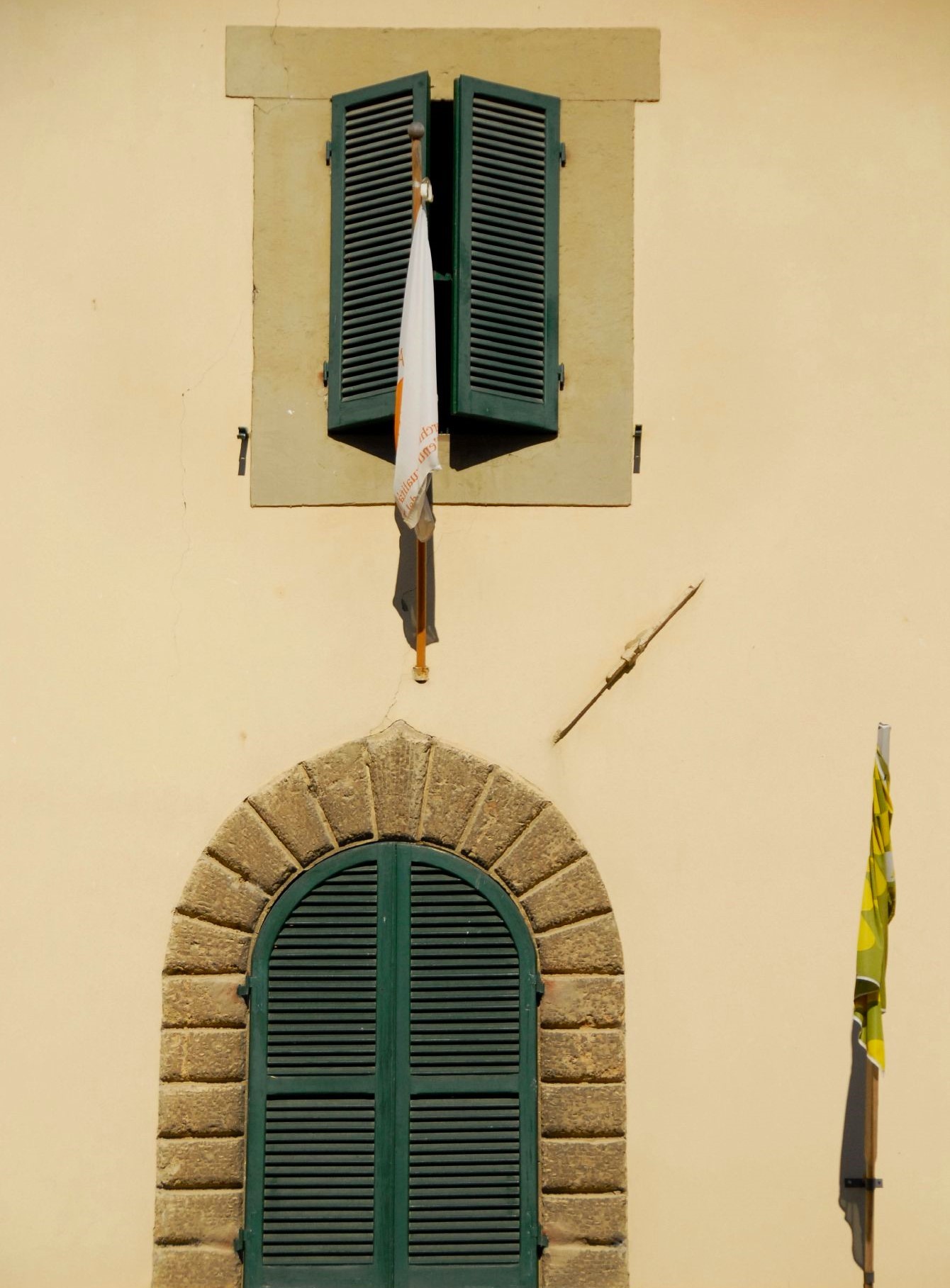 The front facade of a beige stone building with green shuttered windows