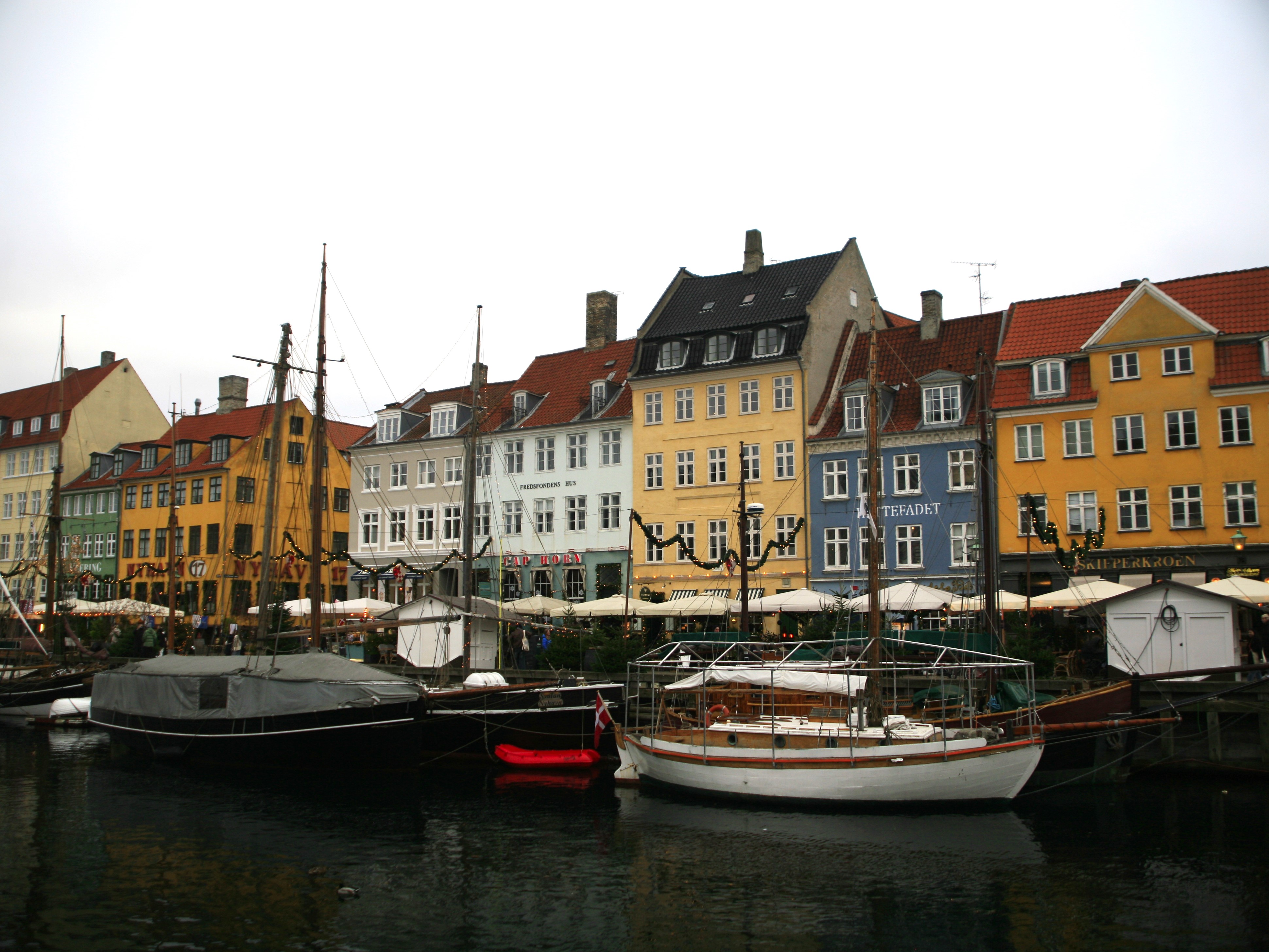 Sailboats floating in the Port of Copenhagen with colourful houses visible in the background