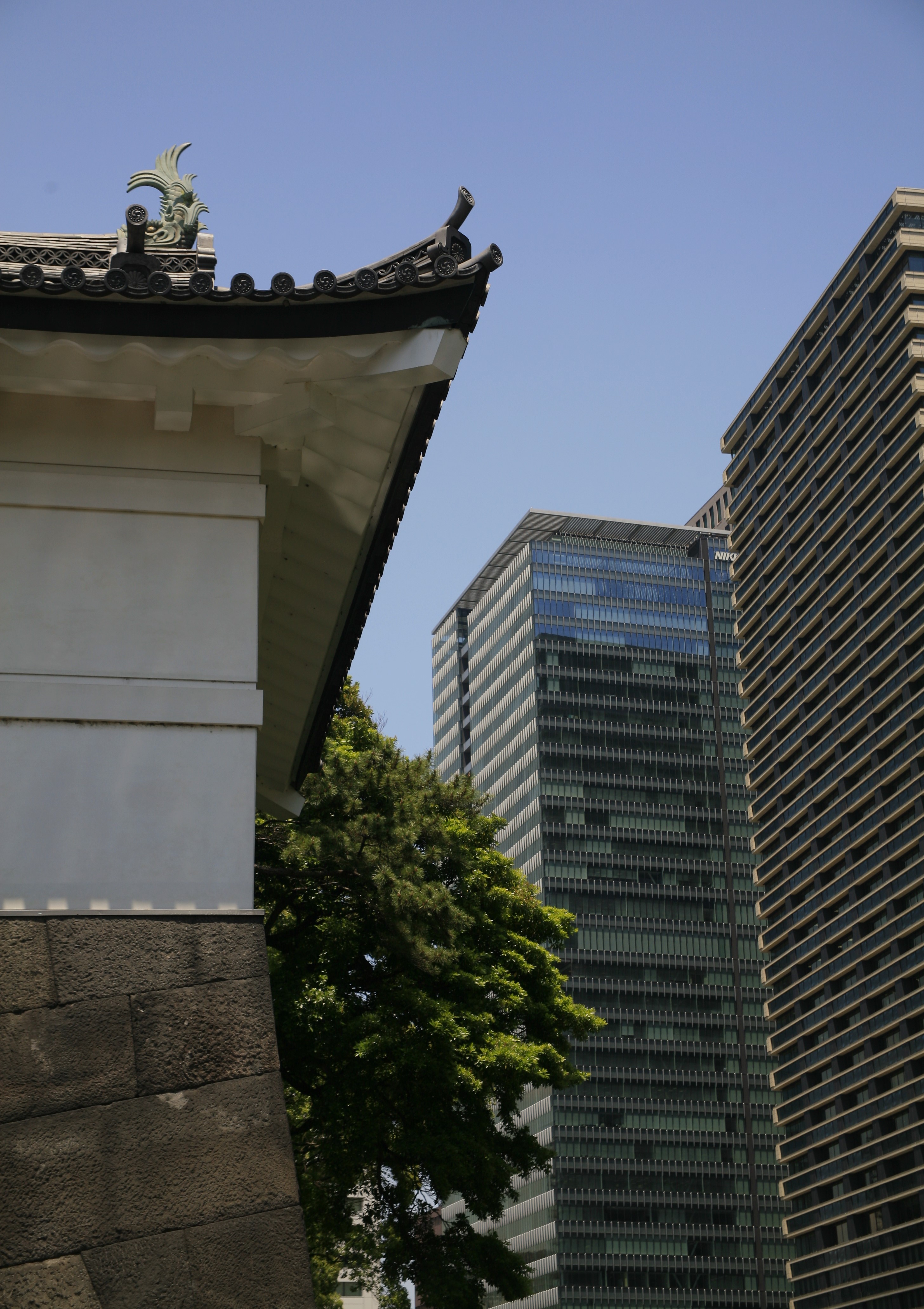 An eave of the Imperial Palace's roof with skyscrapers visible in the background